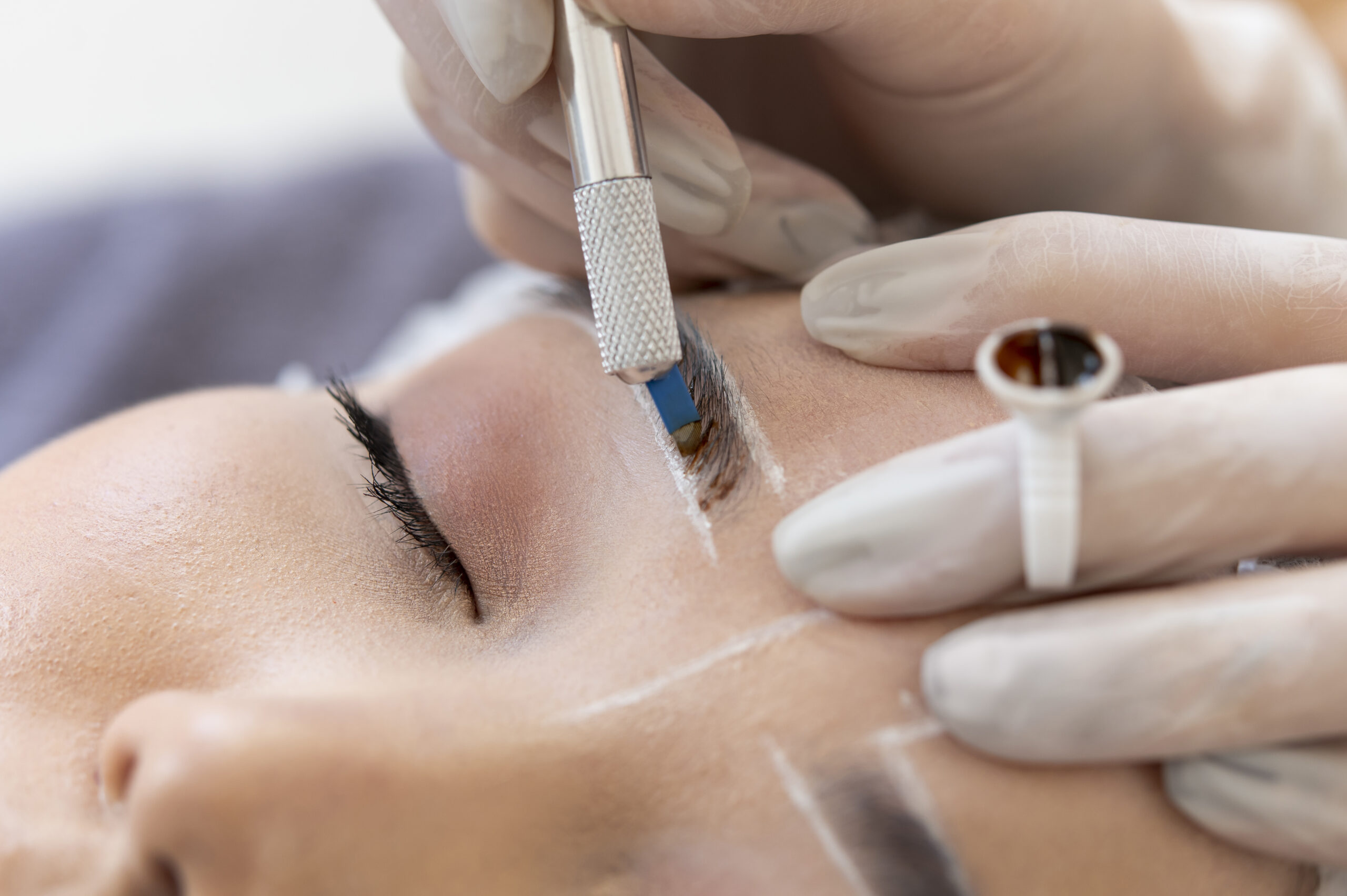 Beautician doing brow lamination procedure on clients eyebrows<br />
