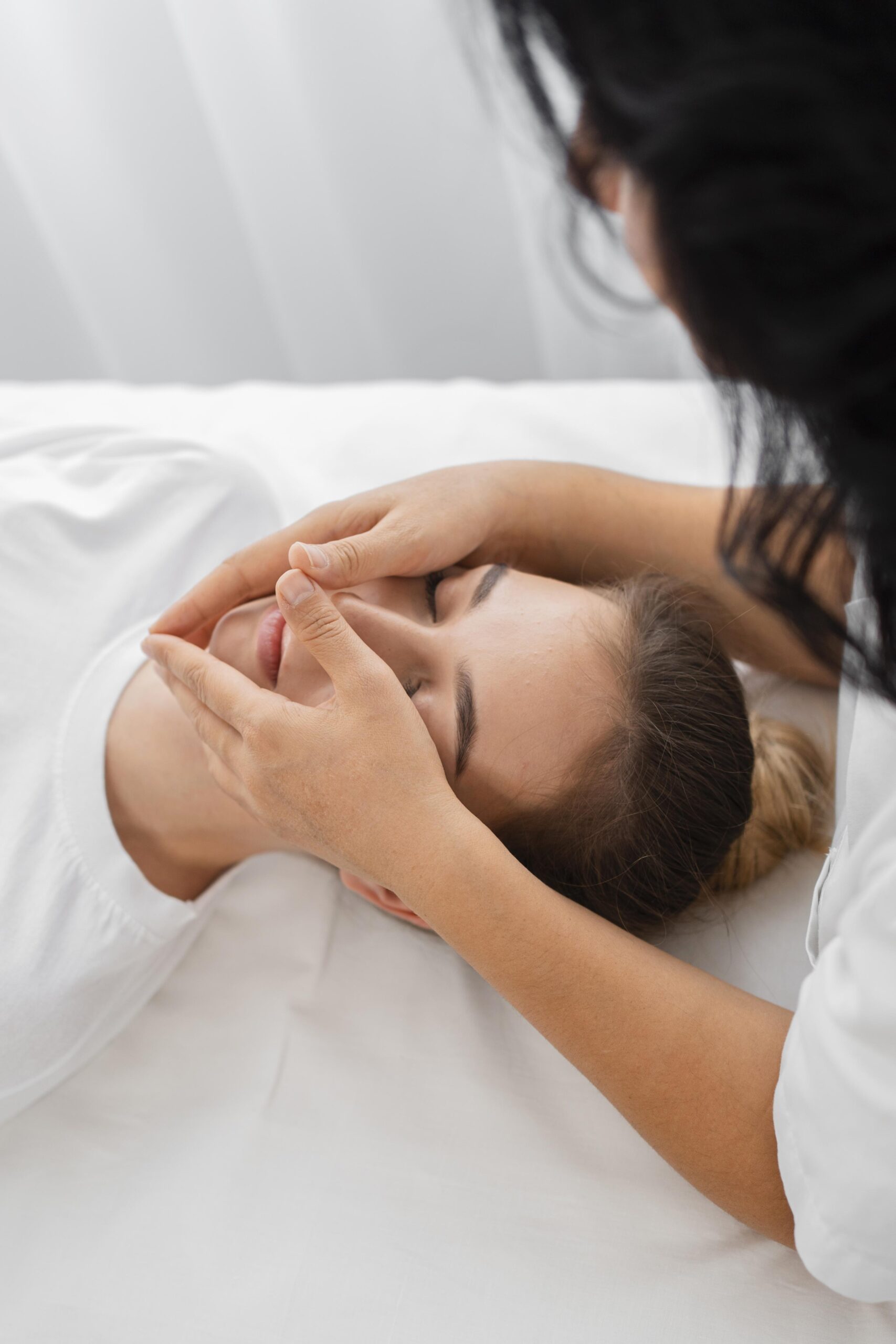 female osteopathist treating patient with chiromassage around chin
