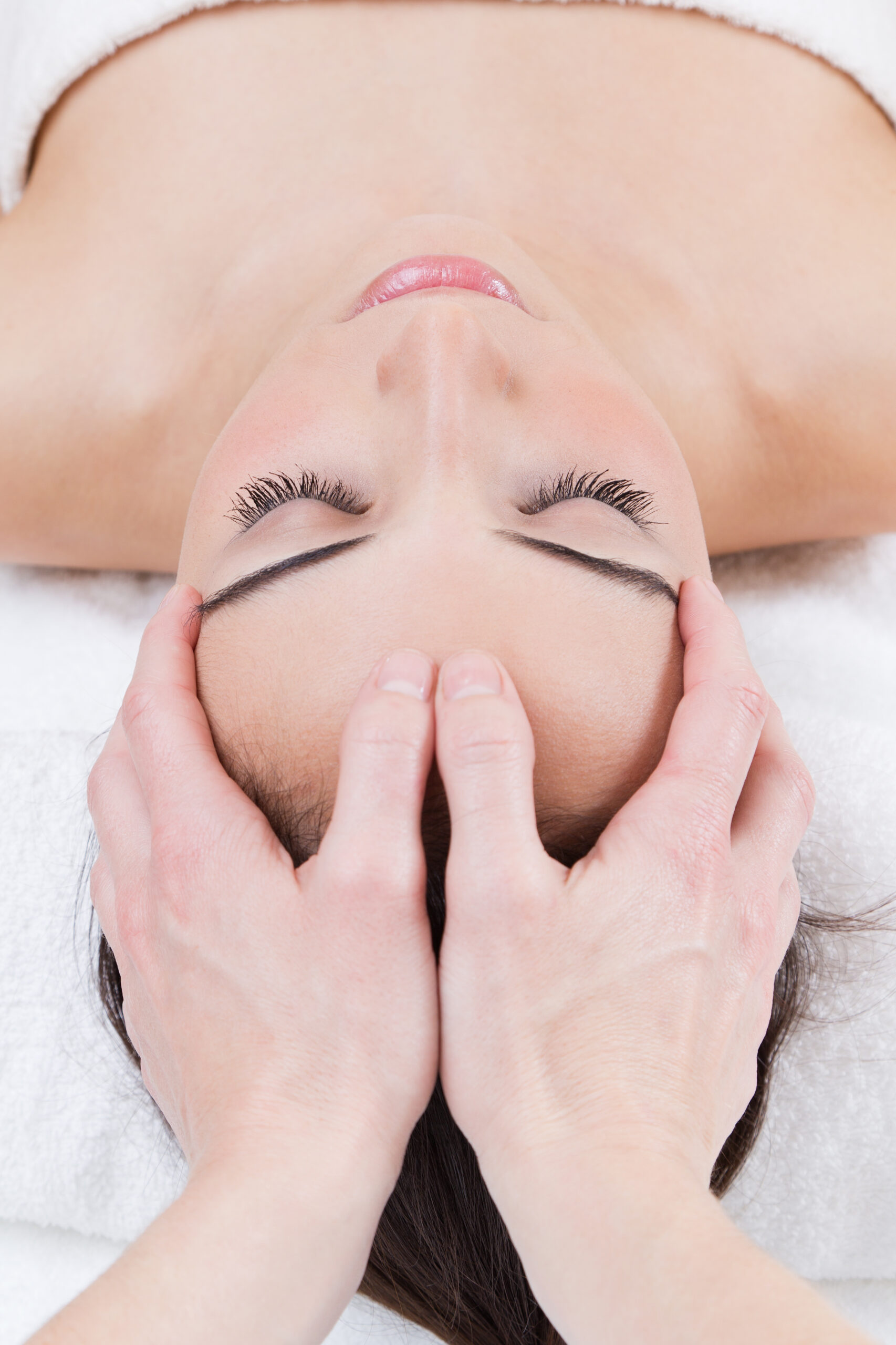 beautician performing a chiromassage on client hands on forehead